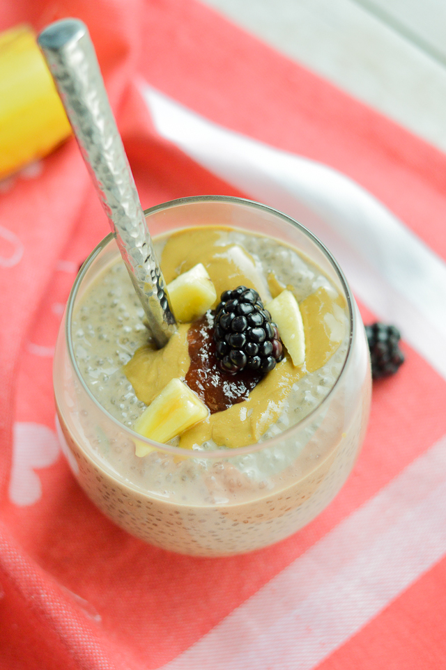 chia pudding with sunflower seed butter bananas and blackberries in a glass with spoon